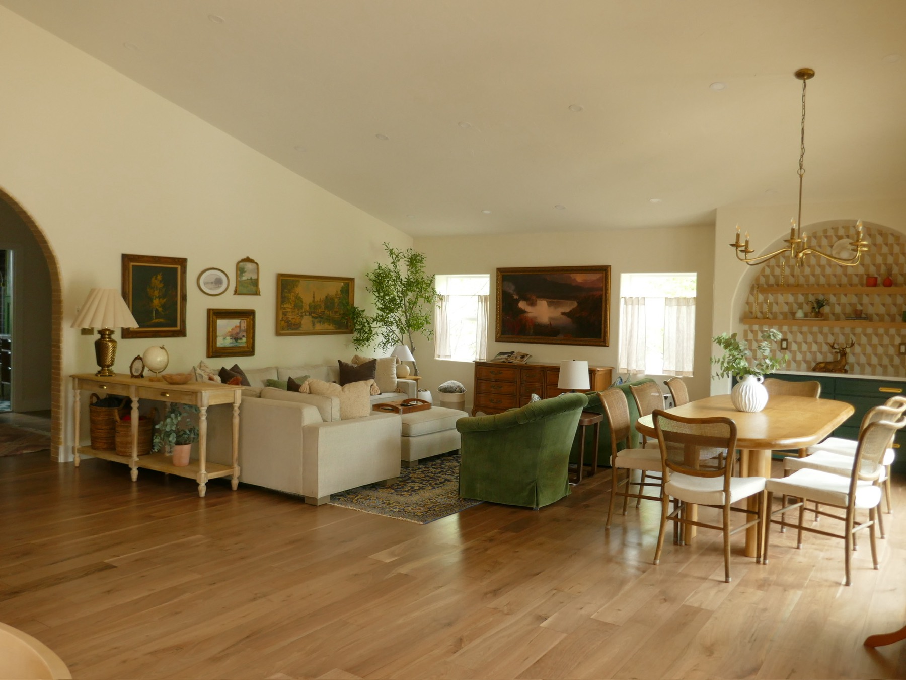 The living and dining great room after the remodel — fully designed and styled with oak floors and a gallery wall